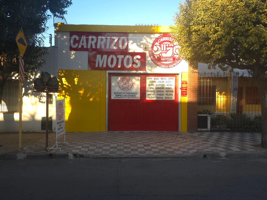 Frente de Carrizo Motos en Emilio Salgari 1279: cartel rojo y blanco sobre fachada amarilla